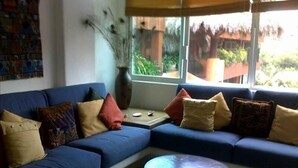 A living room with a blue sofa, a round coffee table, and a vase with dried plants.