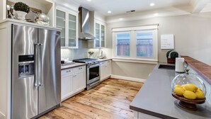 A modern kitchen with stainless steel appliances, white cabinetry, and a wooden floor.