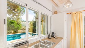 Una cocina moderna con un amplio ventanal con vistas a una piscina, un tostador y un lavamanos.