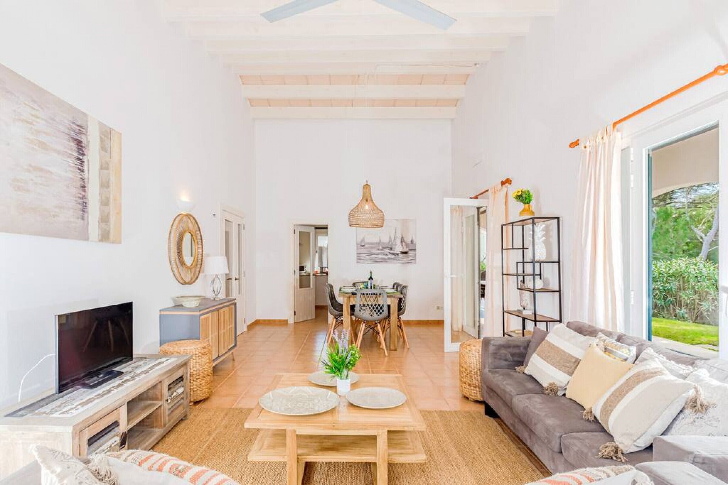 Ein geräumiges Wohnzimmer mit Fernseher, Essbereich und einer Couch mit Kissen.