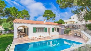 Una villa moderna con piscina, mobiliario de exterior y una pared de piedra.