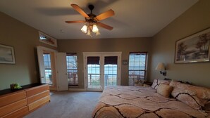 A bedroom with a bed, dresser, ceiling fan, and large windows. - Fox Den- MAGNIFICENT Lake View! 5 minute walk or drive to shoreline!  (Garfield)