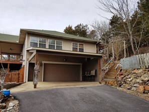 A two-story house with a garage, a covered porch, and a wooden fence.