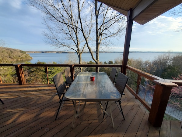 A wooden deck with a table and chairs overlooking a lake.