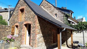 A stone building with a steeply pitched roof, wooden doorways, and a small window. - Holiday house 10 people in Binic (22) with Family or friends. (Binic)