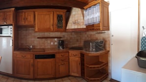 A kitchen with wooden cabinets, a microwave, a refrigerator, and a sink. - Holiday house 10 people in Binic (22) with Family or friends. (Binic)
