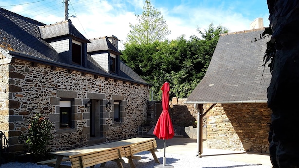 A stone building with a wooden bench and a red umbrella. - Holiday house 10 people in Binic (22) with Family or friends. (Binic)