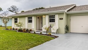 A single-story house with a front porch, a garage, and a well-maintained lawn. - 🍹🌞 Cottage Paradise! 2BR/2BA, Pets Welcome, TV, Wi-Fi (Sebastian)
