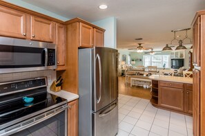A modern kitchen with stainless steel appliances, wooden cabinets, and a dining area with a table and chairs.