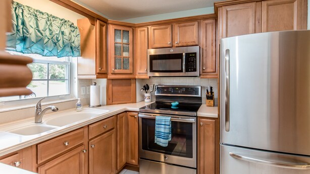 A modern kitchen with wooden cabinets, stainless steel appliances, and a large window with a view. - 🍹🌞 Cottage Paradise! 2BR/2BA, Pets Welcome, TV, Wi-Fi (Sebastian)