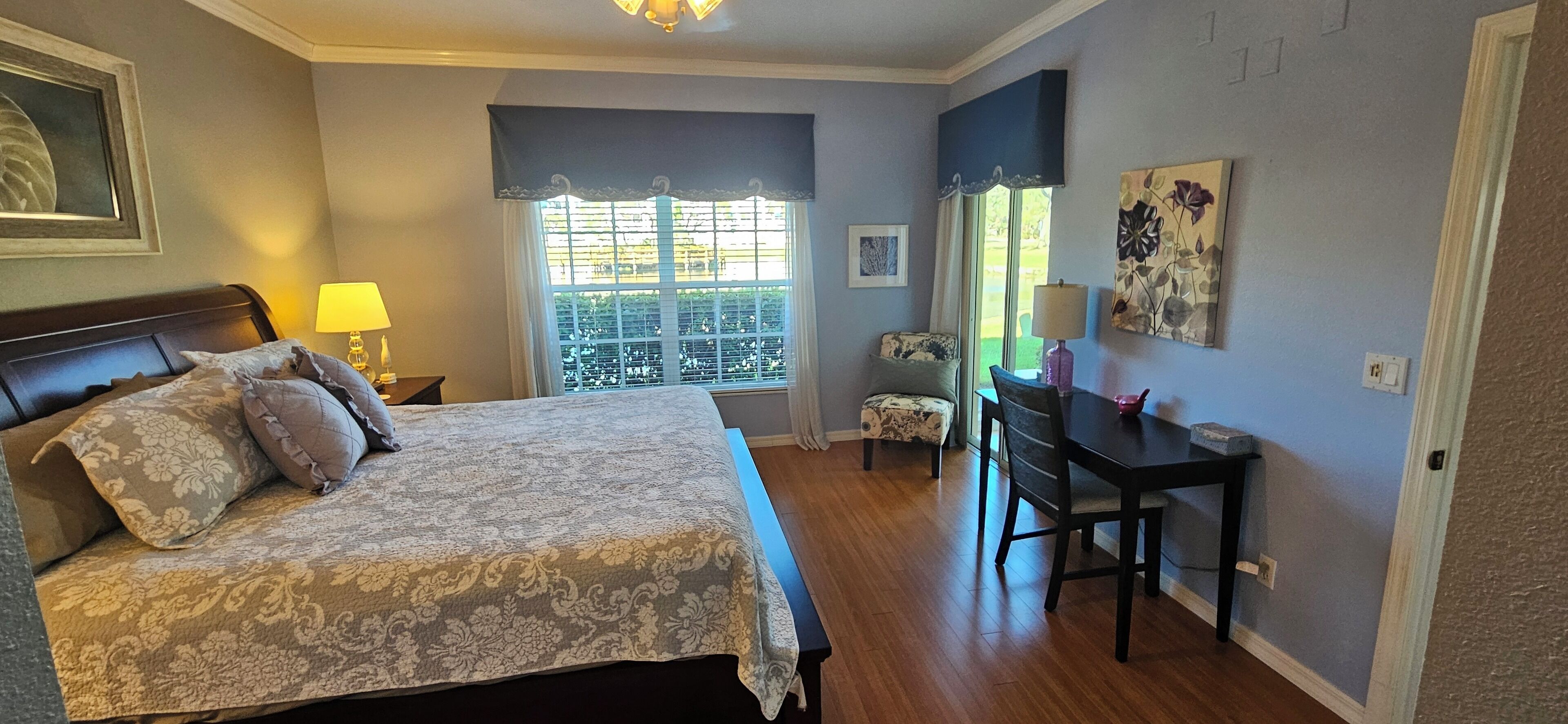 Ein Schlafzimmer mit Bett, Schreibtisch und Fenster mit Balkonblick.