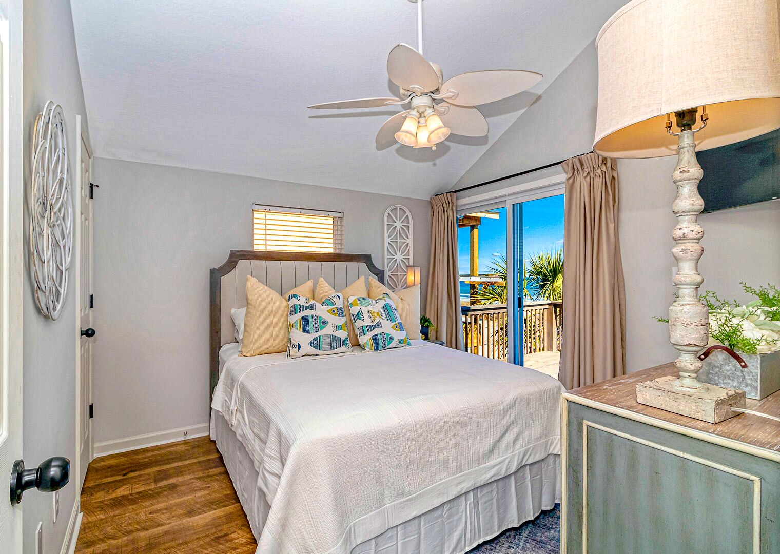 A bedroom with a bed, a ceiling fan, a window, and a view of the outdoors.
