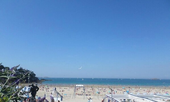 A beach with people, boats, and a clear sky.