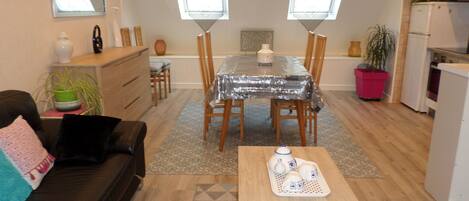 A compact living space with a dining area, kitchenette, and a sofa.