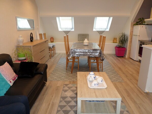 A compact living space with a dining area, kitchenette, and a sofa.