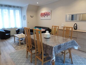 Un comedor con una mesa cubierta por un mantel estampado, rodeado de sillas de madera.