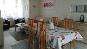 Una sala de estar acogedora con una mesa de comedor, sillas, un sofá y una mesa de centro.