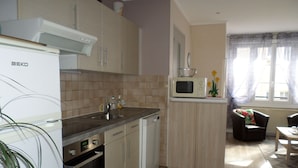Una cocina moderna con horno empotrado, microondas y lavaplatos. Hay una pequeña zona de comedor con una mesa y sillas.