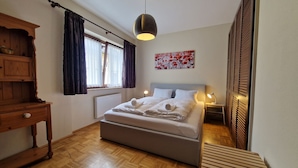 A neatly arranged bedroom with a bed, bedside lamps, a radiator, and a wooden dresser. - Apartment Centrum für 4 Personen (Zell am See)