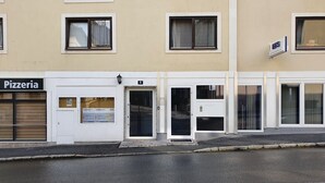 A building with a closed shutter on the left labeled "Pizzeria," a door with a number "8" above it, and a sign indicating "EFS" on the right. - Apartment Centrum für 4 Personen (Zell am See)