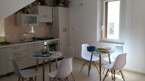 Una cocina moderna con armarios blancos, una mesa de comedor con sillas y una ventana con vistas.