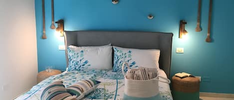 A bedroom with a bed, pillows, a bedside table, and wall-mounted lights.