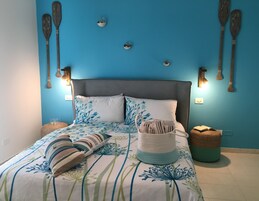 Camera da letto con un letto, cuscini, comodino e luci a parete.