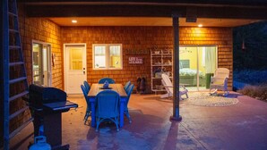A covered patio with a brick wall, a table with chairs, a grill, and a sliding glass door leading to a bedroom. - Charming "Cherry House" (Rollins)