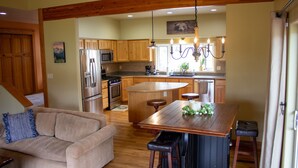 A spacious kitchen with wooden cabinets, a central island, and a dining area with a wooden table and bar stools. - Charming "Cherry House" (Rollins)