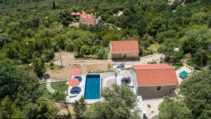Una vila amb piscina, envoltada de vegetació abundant i un paisatge de muntanyes.