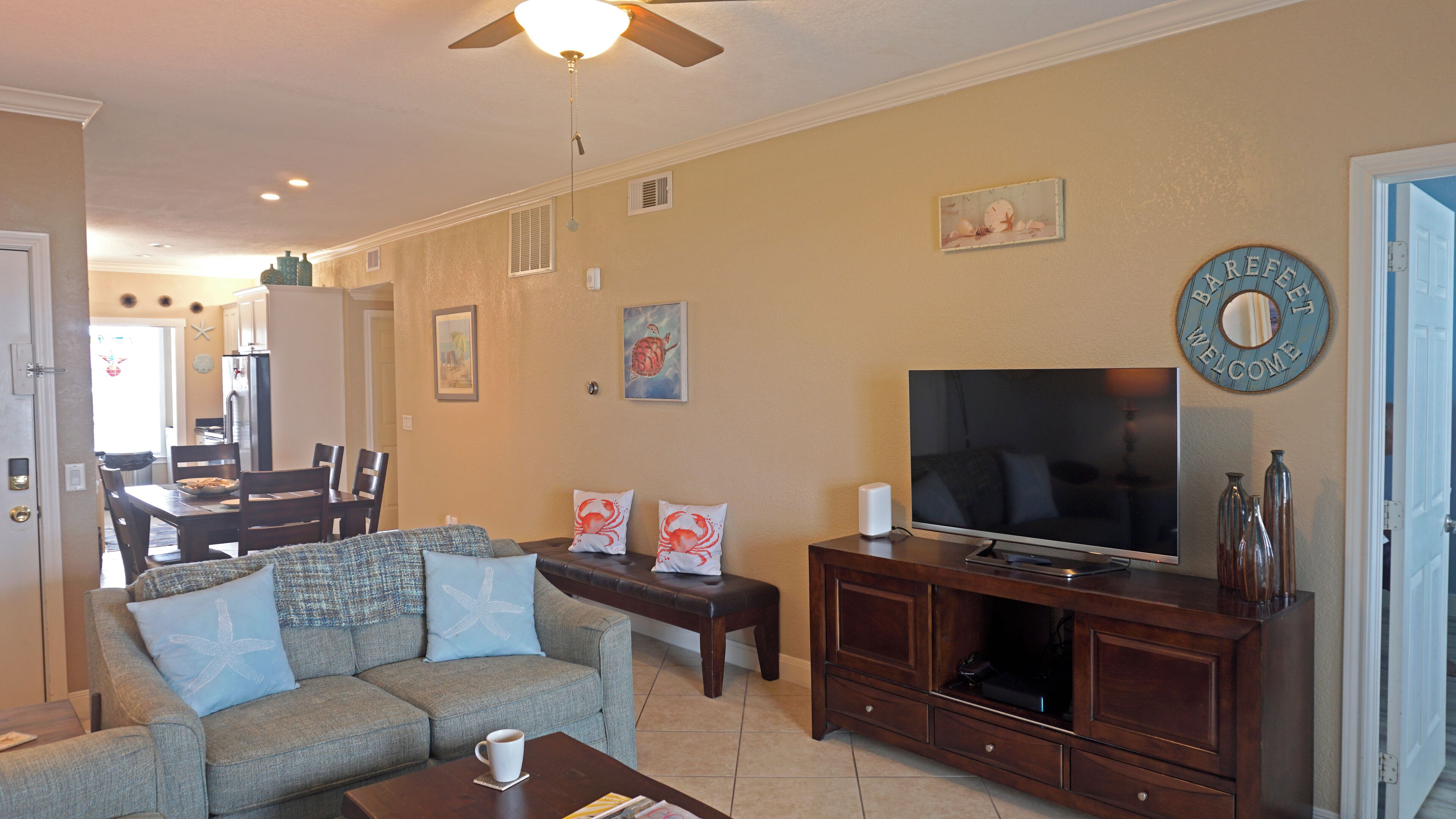 A living room with a sofa, coffee table, TV, and a dining area with chairs and a table.