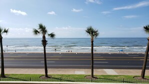 A coastal road with palm trees and a beach in the background. - Dawn 1024 (Galveston)