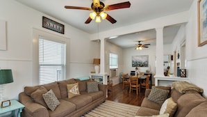 A living room with a brown sofa, a teal side table, and a ceiling fan. - Tina Marie (Galveston)