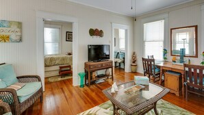 Un salón amplio con televisión, muebles de mimbre, zona de comedor y ventilador de techo.