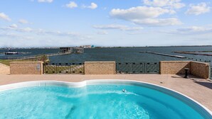 A swimming pool with a view of the water and distant buildings.