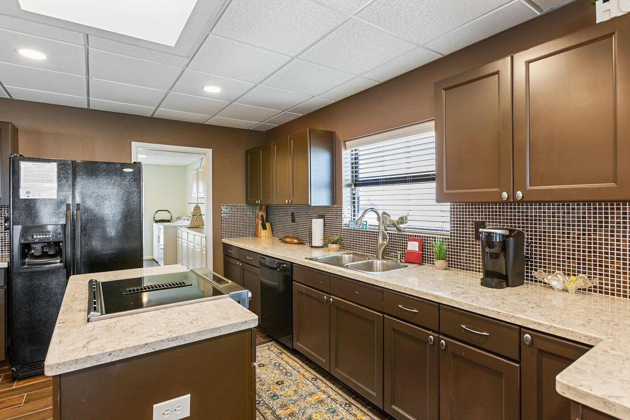 A modern kitchen with a refrigerator, dishwasher, sink, and a coffee maker.