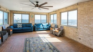 A spacious room with a large window, a ceiling fan, and a blue sofa.
