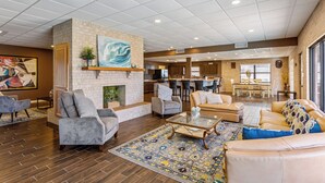 A spacious lobby with a fireplace, comfortable seating, a kitchen area, and a dining space.