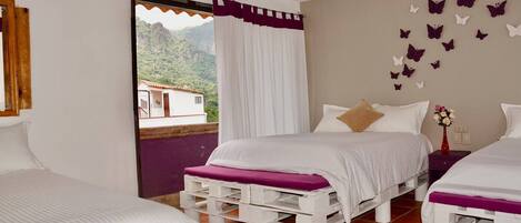 A bedroom with two beds, a window with curtains, a view of mountains, and butterfly wall decals.