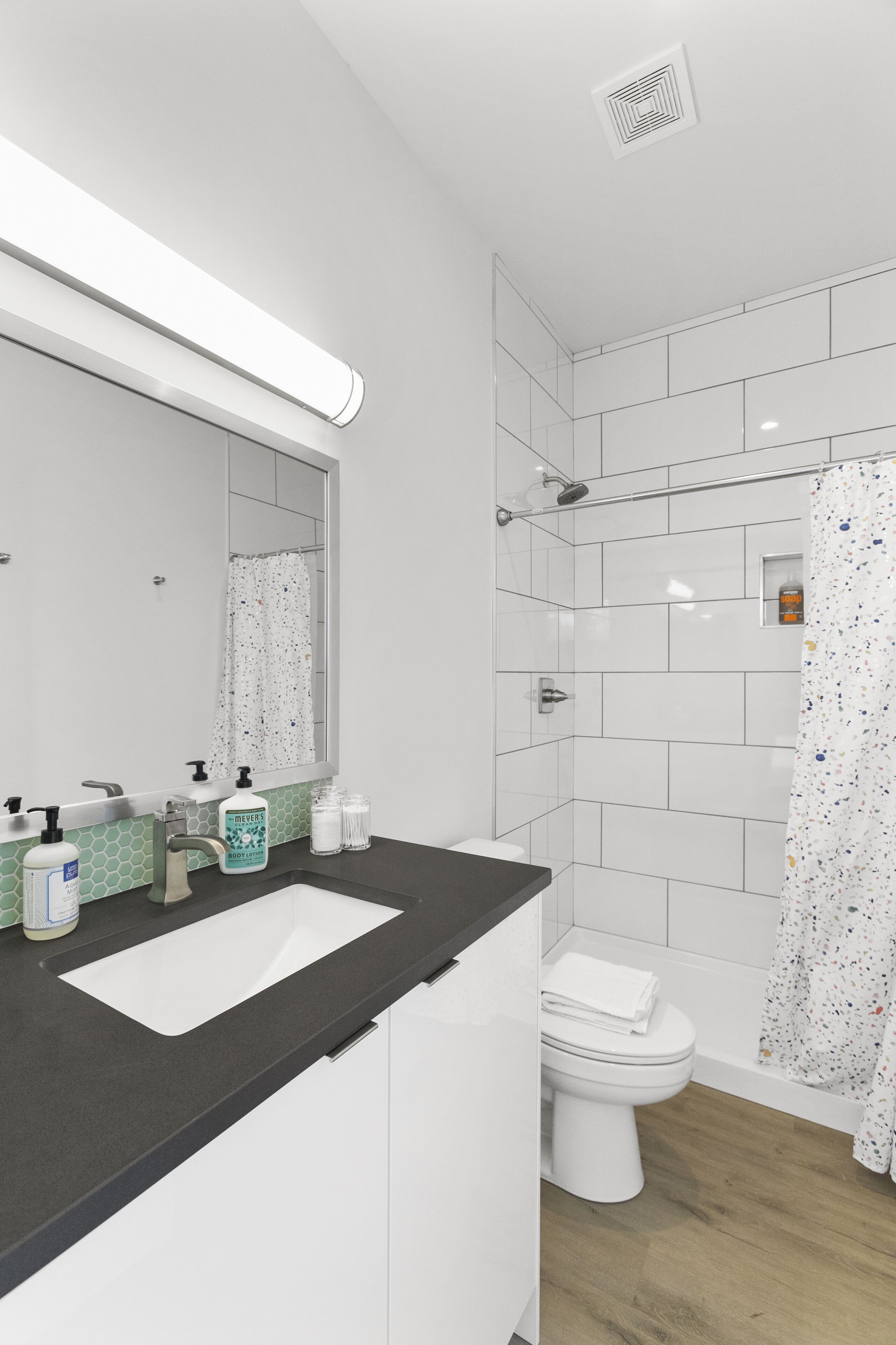 Une salle de bain moderne avec un lavabo blanc, un miroir et une douche.