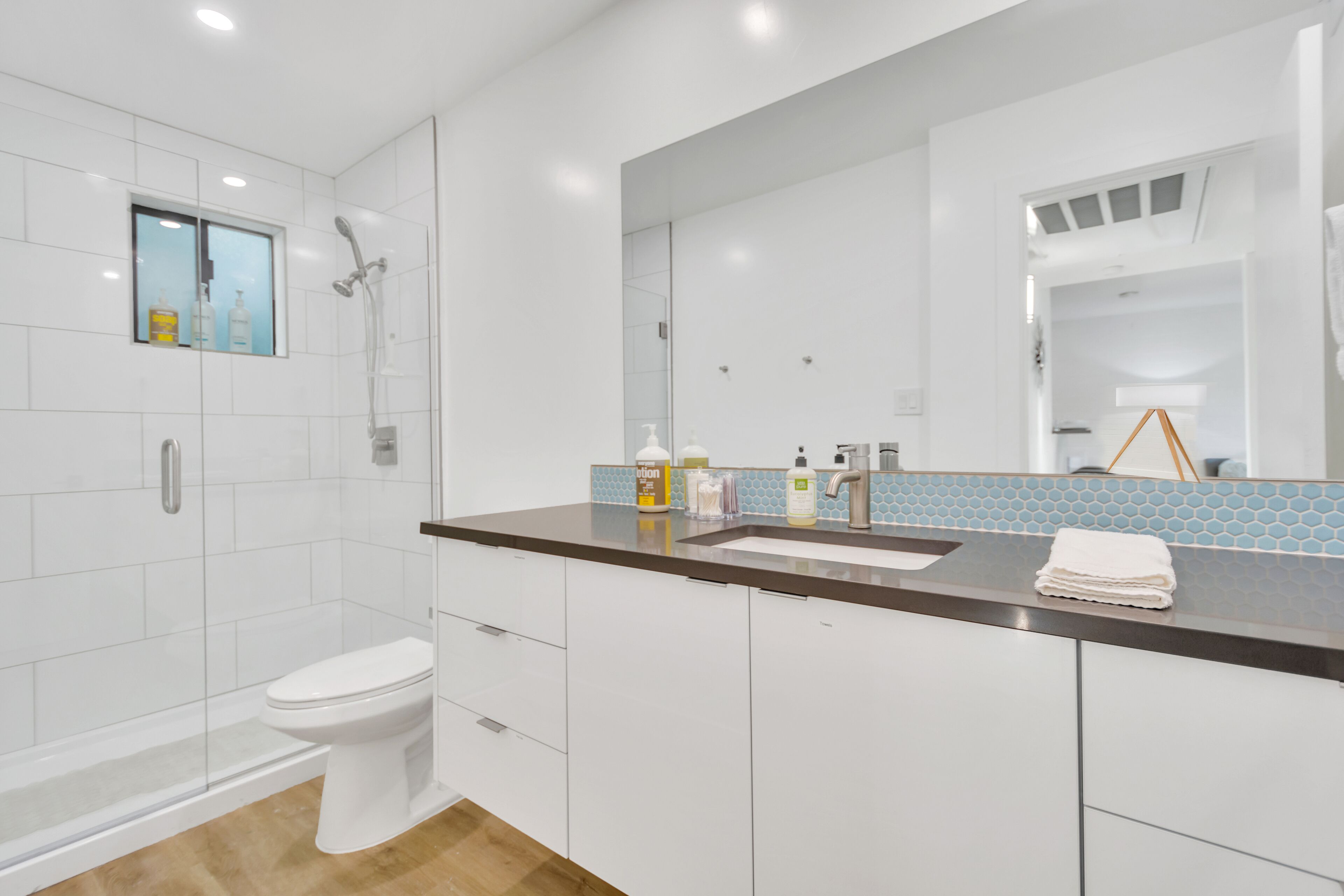 A modern bathroom with a toilet, shower, and sink.
