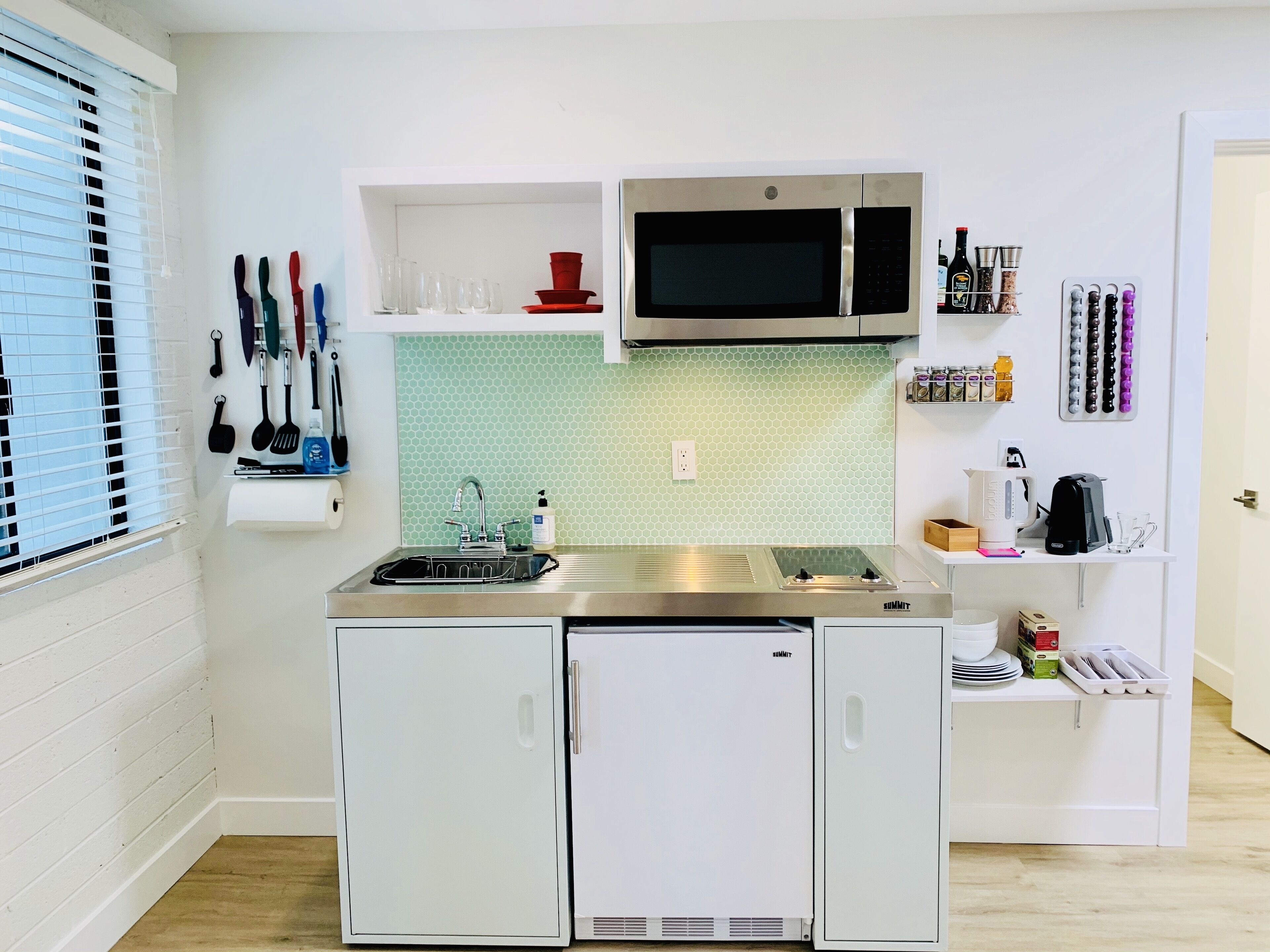 A compact kitchen with a stainless steel sink, a microwave, and a built-in refrigerator.