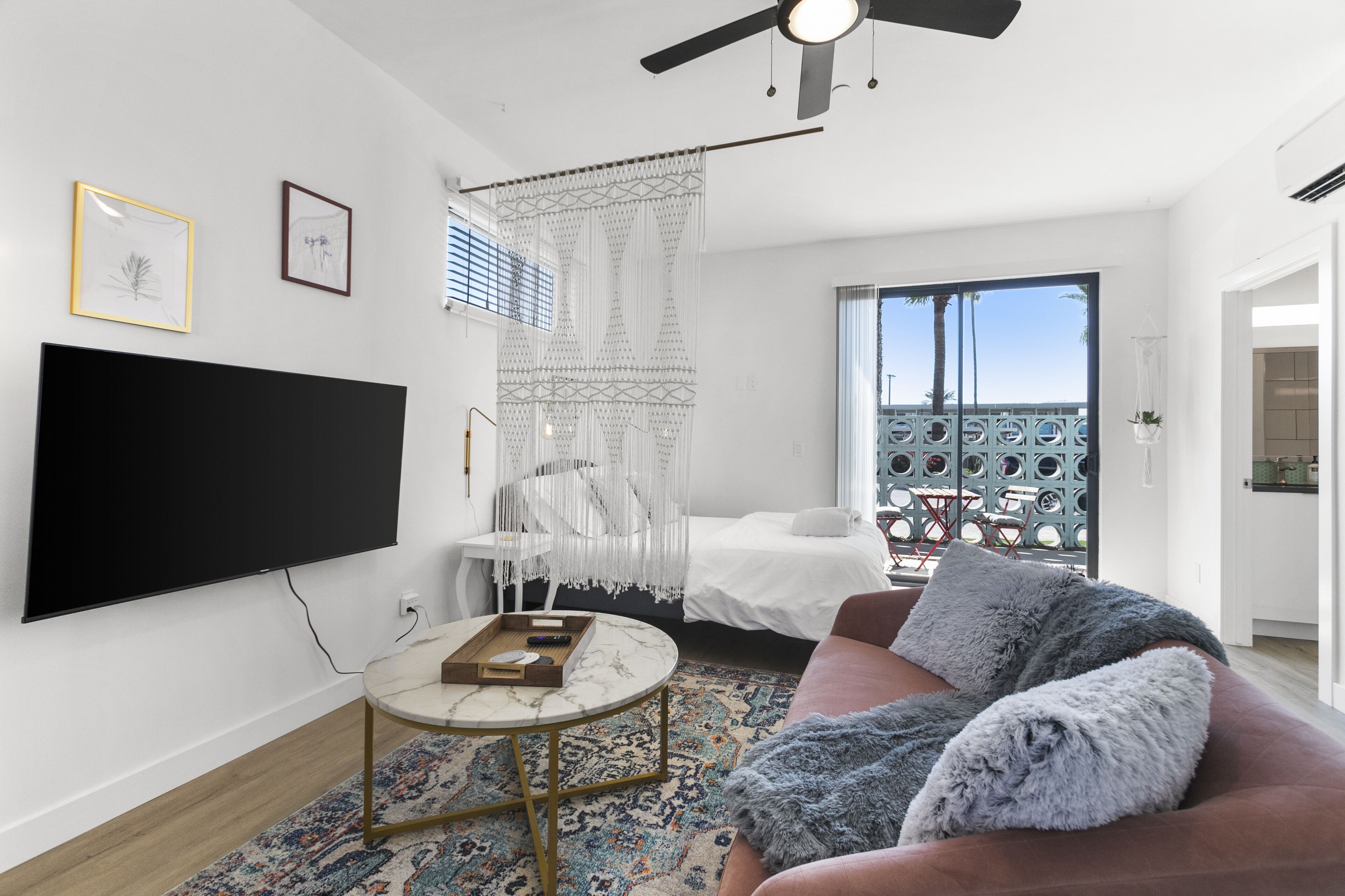 A modern living room with a flat-screen TV, a round coffee table, a sofa, and a balcony with a view.