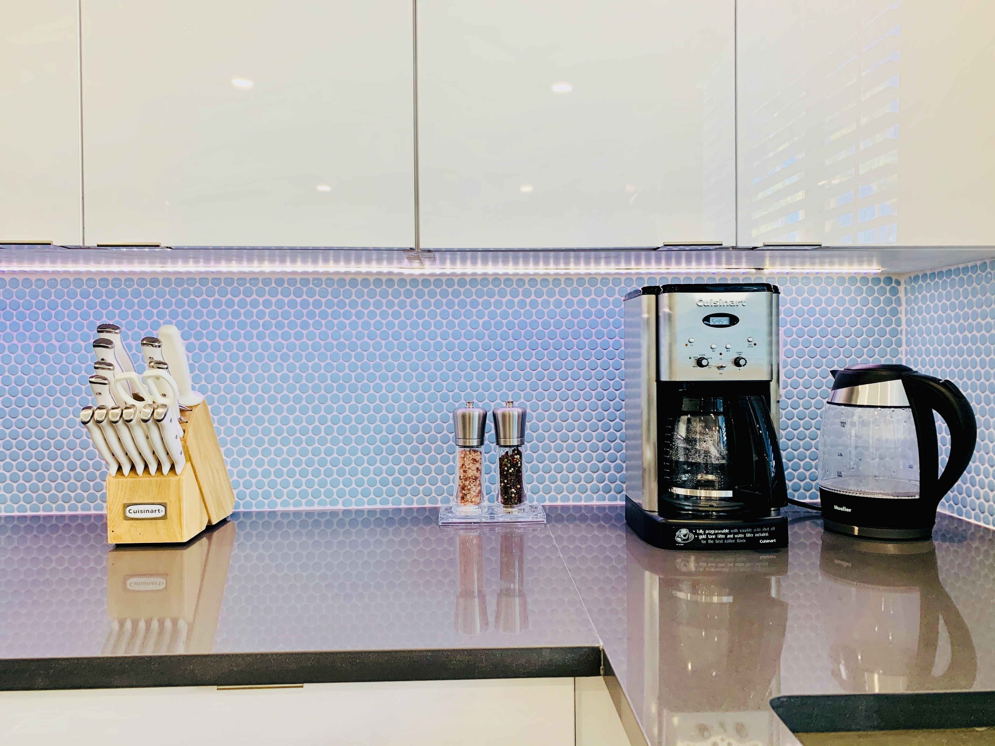 Un plan de travail de cuisine avec une machine à café, un distributeur d’eau et un bloc à couteaux.