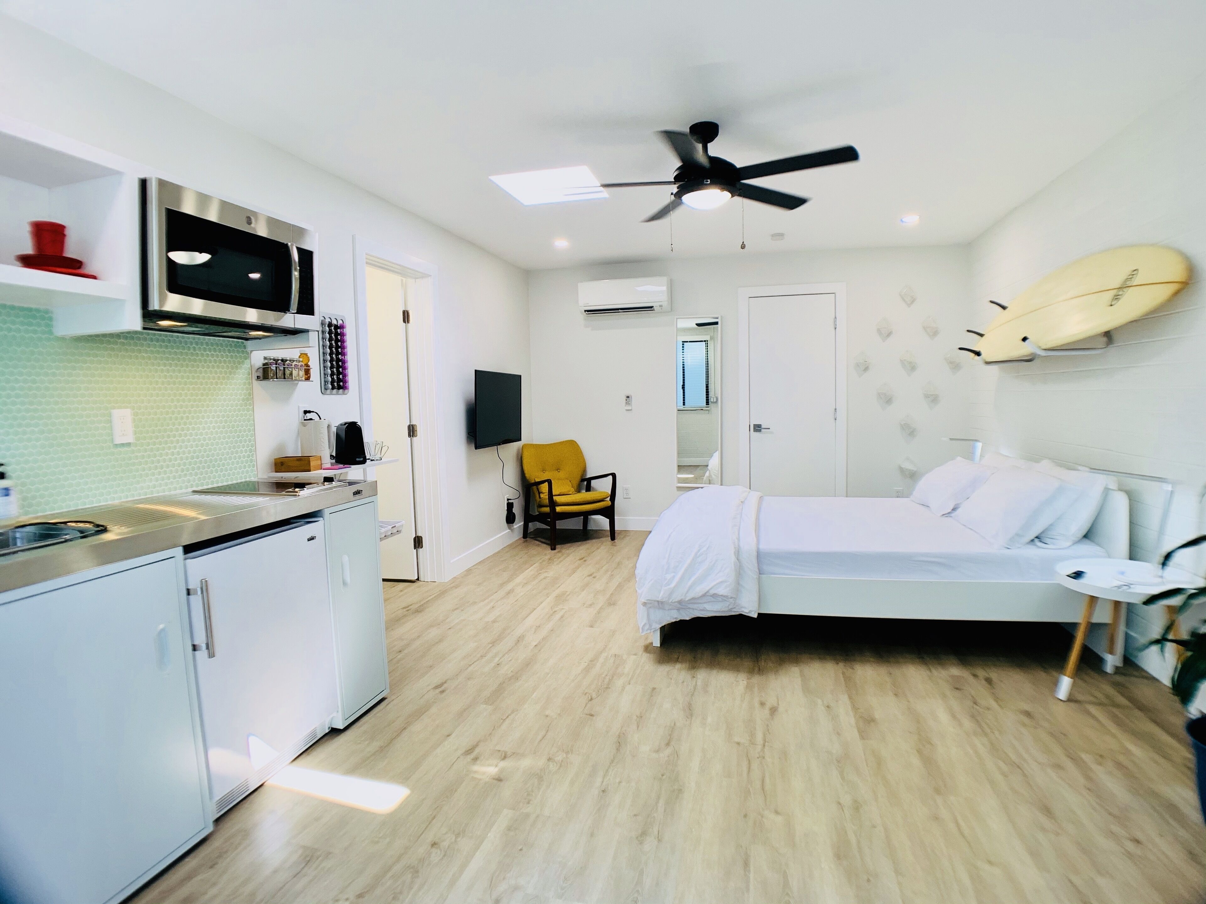 Un dormitorio moderno con una cama, un sillón y un ventilador de techo.