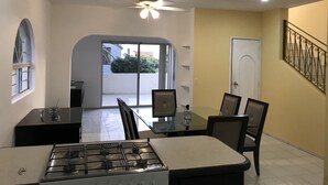 A dining area with a gas stove, chairs, a glass table, and a ceiling fan. - 2 br 2 ba in gated community w/private beach (Cabo San Lucas)