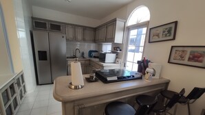 A kitchen with a central island, bar stools, a refrigerator, and a microwave. - 2 br 2 ba in gated community w/private beach (Cabo San Lucas)