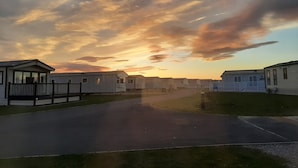 A row of mobile homes with a paved driveway and a grassy area in front. - Taid's Retreat Silversands Cove Beach Lossiemouth (Lossiemouth)
