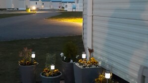 A row of white mobile homes with a paved driveway and potted plants in front. - Taid's Retreat Silversands Cove Beach Lossiemouth (Lossiemouth)