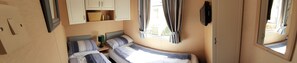 A compact room with two beds, a small table, and a TV mounted on the wall. - Taid's Retreat Silversands Cove Beach Lossiemouth (Lossiemouth)